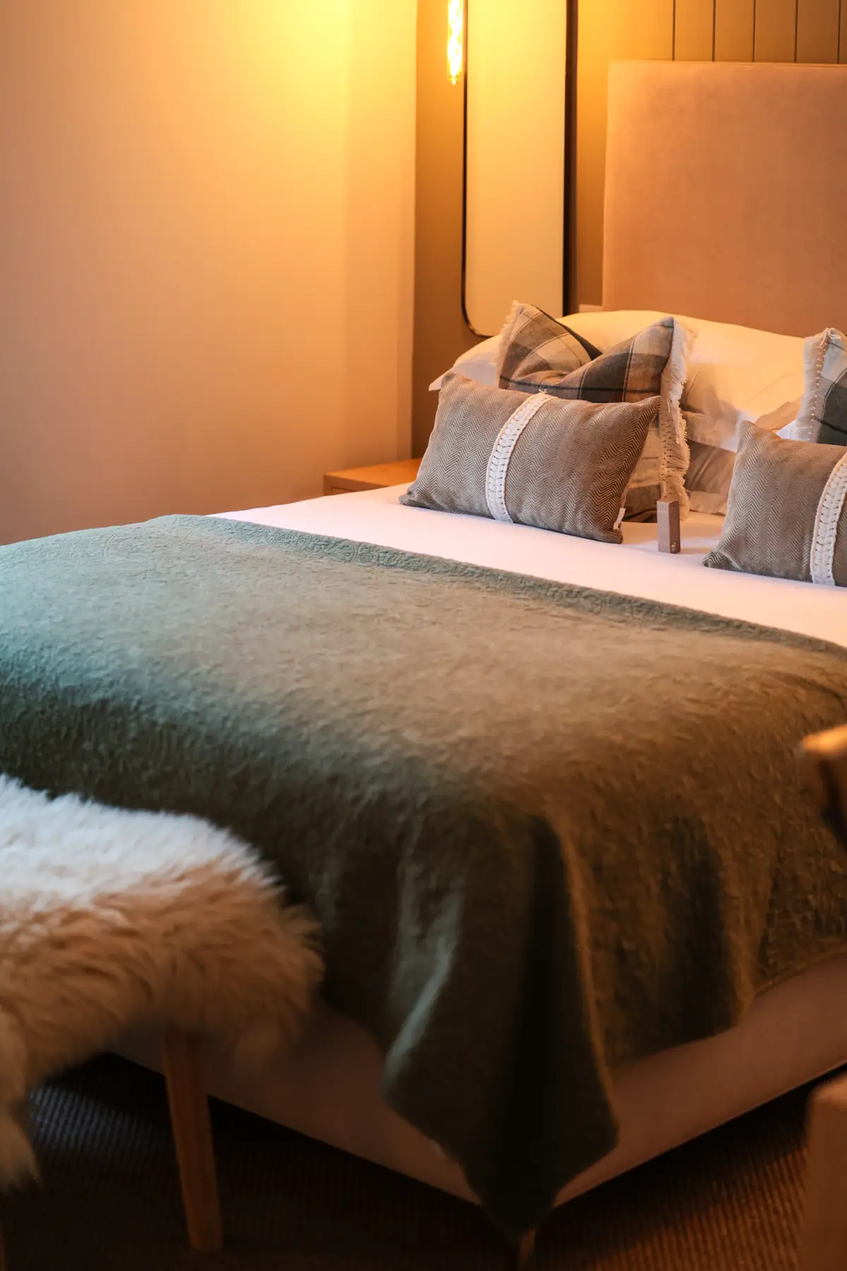 Bed with a green throw and sheepskin