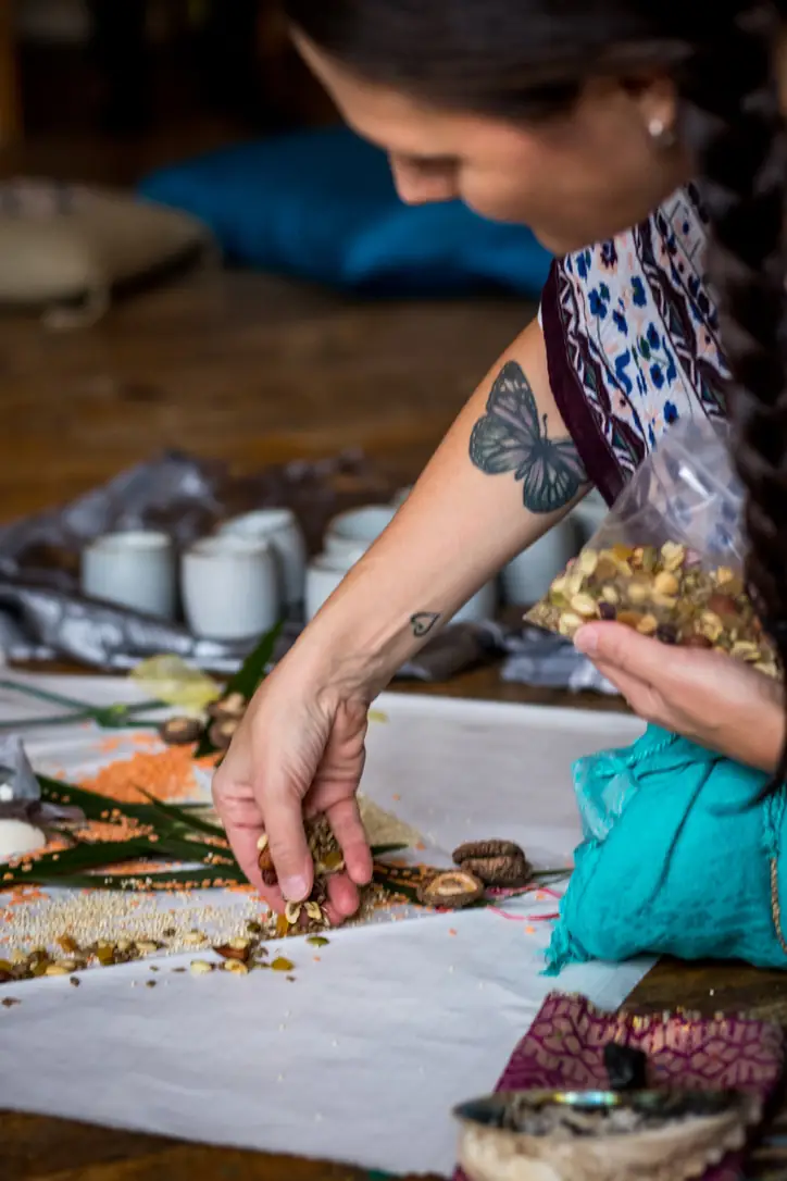 Hands preparing a ceremonial altar with flowers and herbs